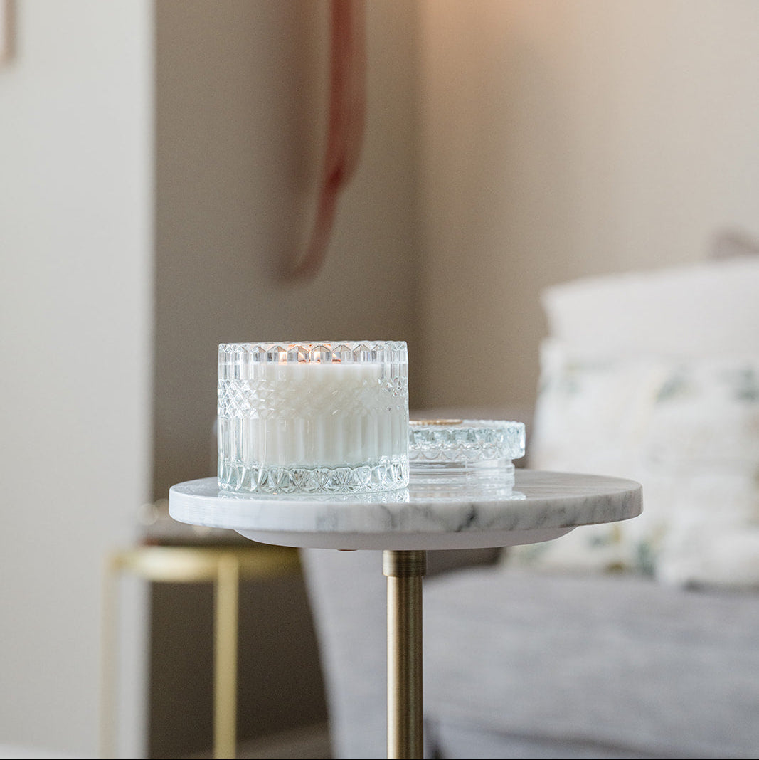 Glass candle holders on a marble side table with a blurred background