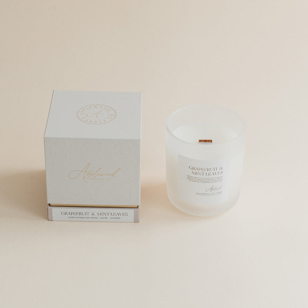Grapefruit & Mint Leaves candle in frosted glass jar with box on beige background.