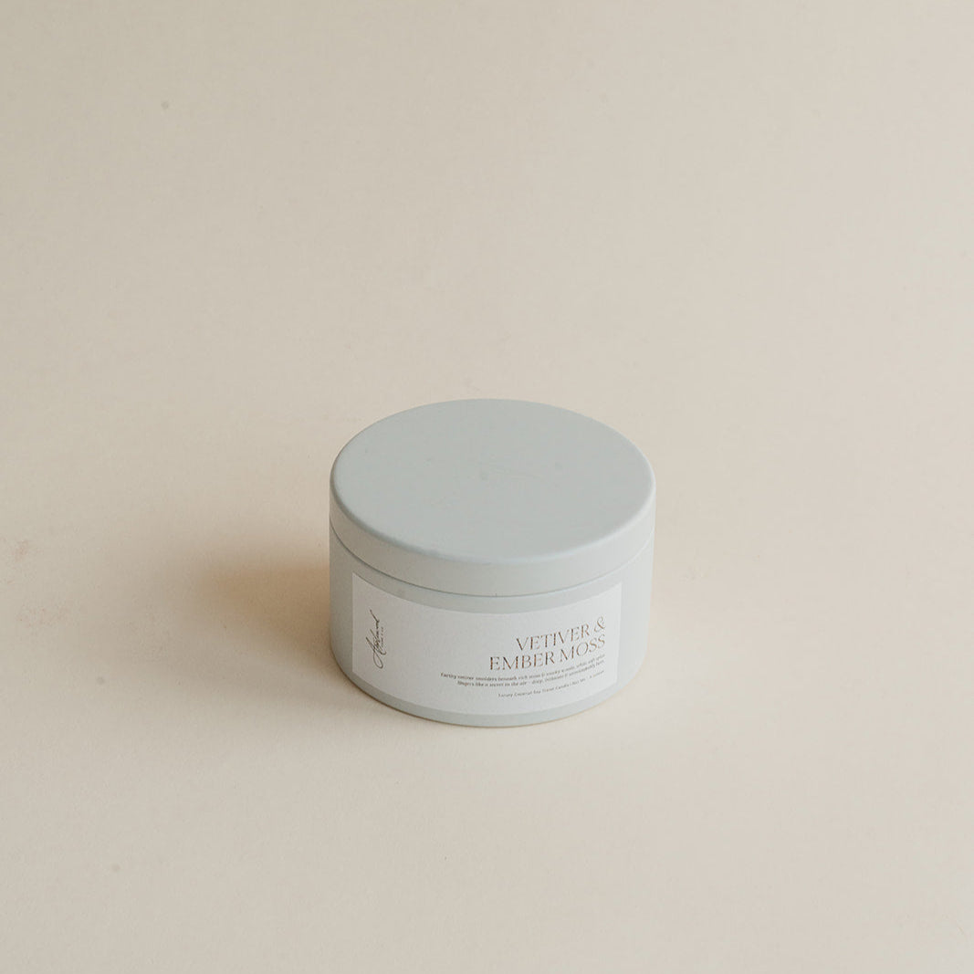 Vetiver & Ember Moss travel candle in tin can on beige background