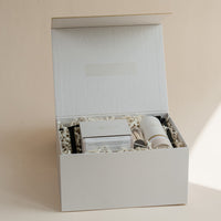 Luxury custom gift box with luxury candle,  room linen & mist, candle snuffer, wick trimmer and set of matches on beige background.