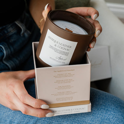 Antique Leather &amp; Cognac candle in brown glass jar being placed inside a box.