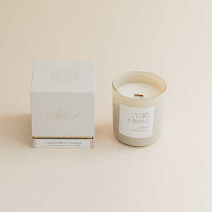 Cashmere &amp; Vanilla candle in frosted glass jar with box on beige background.