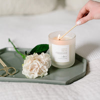 Citrus Grove Candle in glass frosted jar being lit.