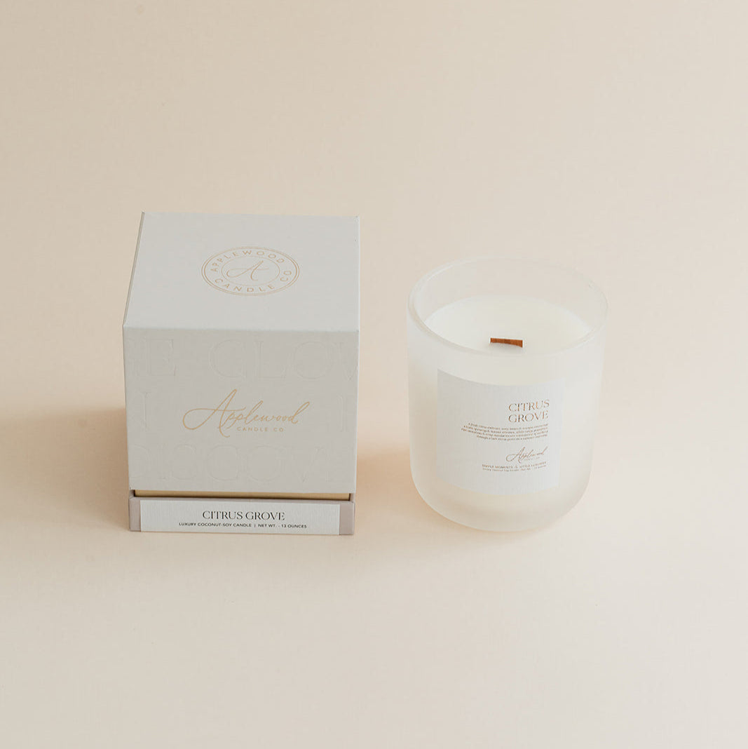 Citrus Grove candle in frosted glass jar with box on beige background.