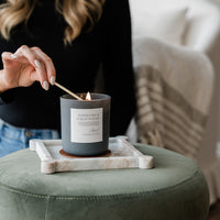 Peppercorn & Forest Woods Candle in frosted glass jar being lit.