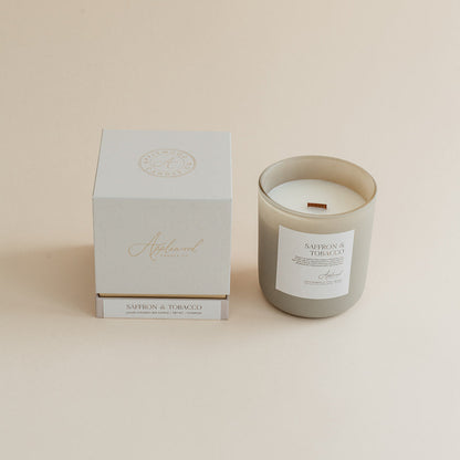 Saffron &amp; Tobacco candle in frosted glass jar with box on beige background.