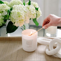 Sea Salt & Teakwood Candle in glass frosted jar being lit.