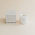 Sea Salt & Teakwood candle in frosted glass jar with box on beige background.
