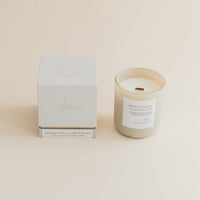 Shea Butter & Sandalwood candle in frosted glass jar with box on beige background.
