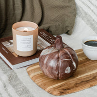 Lit Vetiver & Ember Moss candle on cozy background