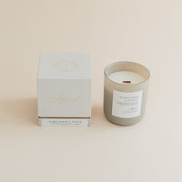 Warm Amber & Santal candle in frosted glass jar with box on beige background.