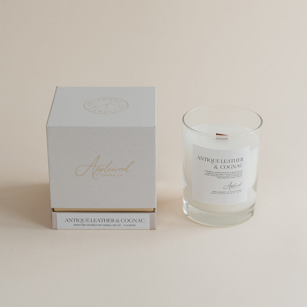 Antique Leather &amp; Cognac candle in clear glass jar with box on beige background.
