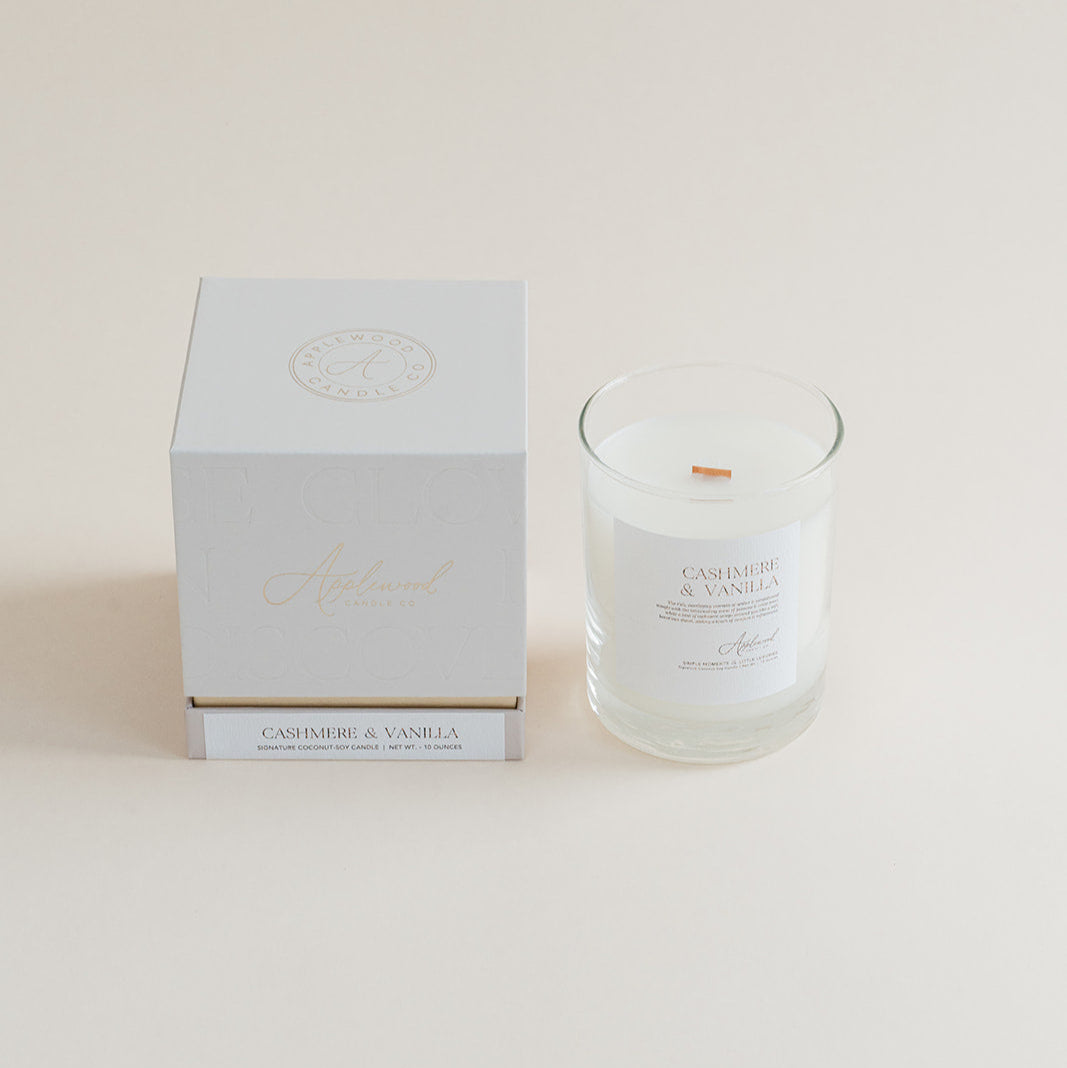 Cashmere &amp; Vanilla candle in clear glass jar with box on beige background.