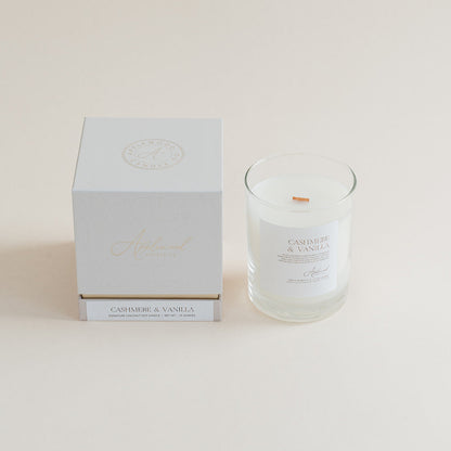 Cashmere &amp; Vanilla candle in clear glass jar with box on beige background.
