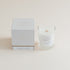 Cashmere & Vanilla candle in clear glass jar with box on beige background.