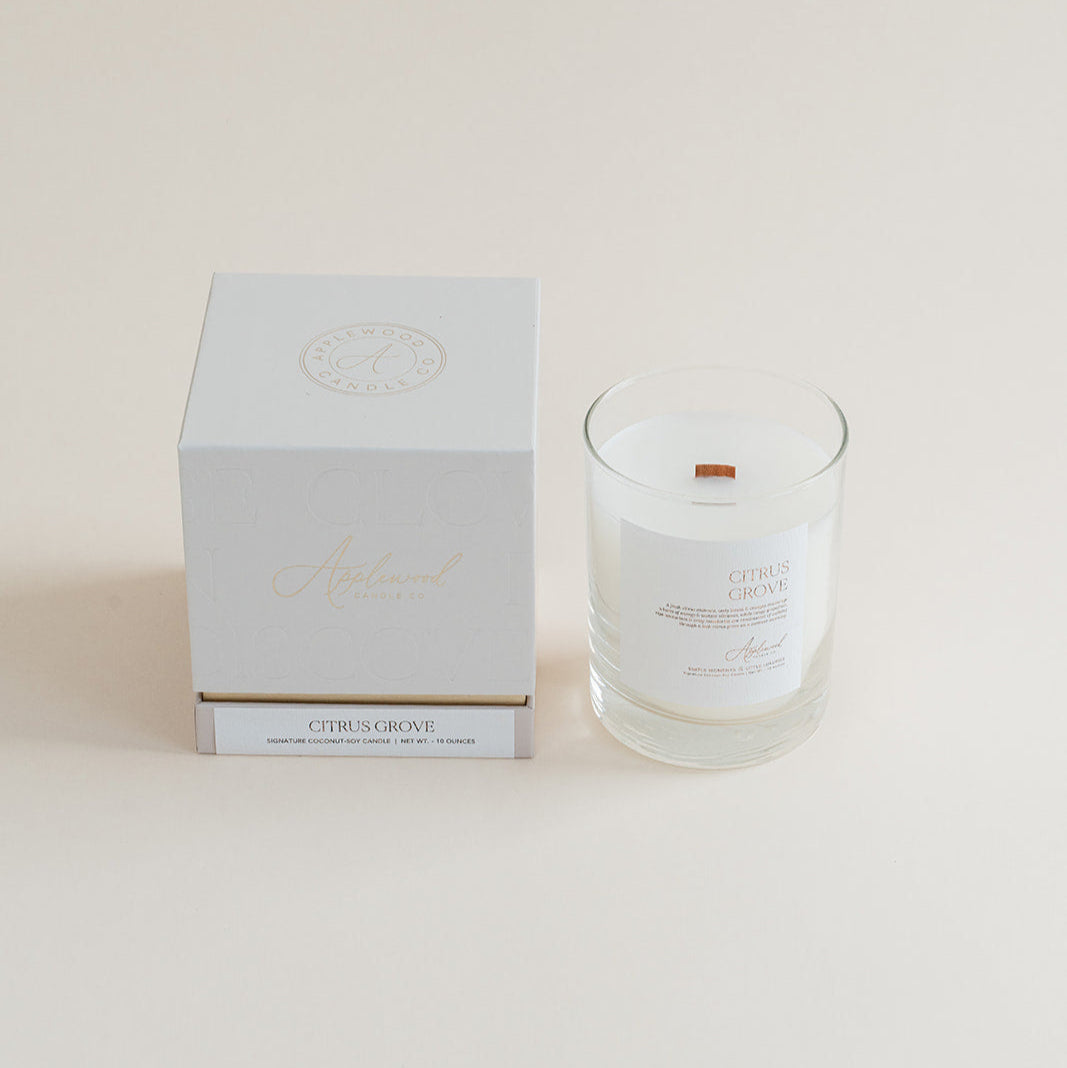 Citrus Grove candle in clear glass jar with box on beige background.