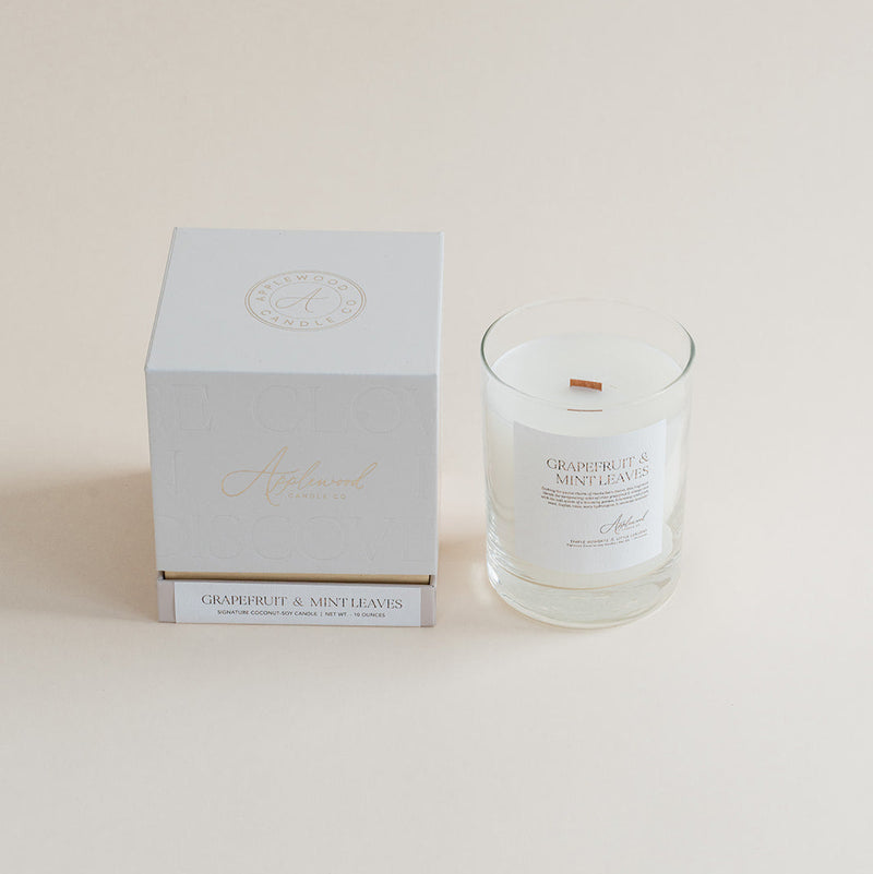 Grapefruit & Mint Leaves candle in clear glass jar with box on beige background.