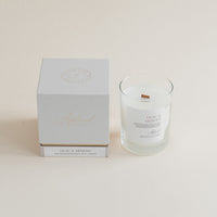 Lilac & Mimosa candle in clear glass jar with box on beige background.