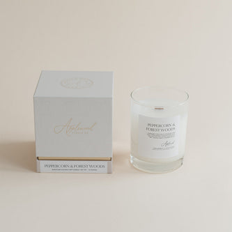 Peppercorn & Forest Woods candle in glass jar with box on beige background.