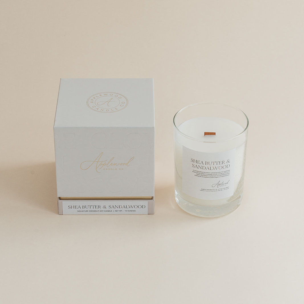 Shea Butter & Sandalwood candle candle in glass jar with box on beige background.