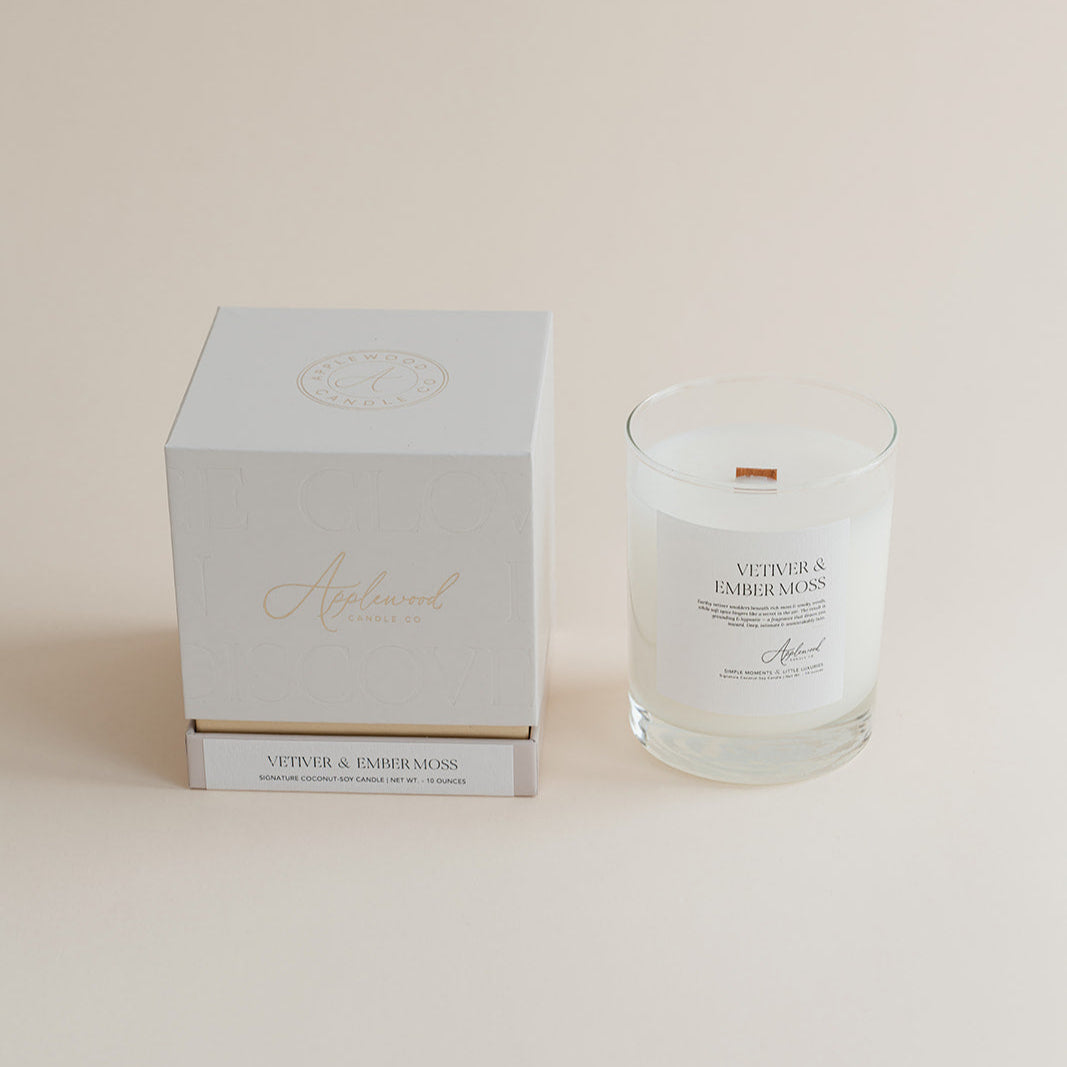 Vetiver & Ember Moss signature candle with box on beige background