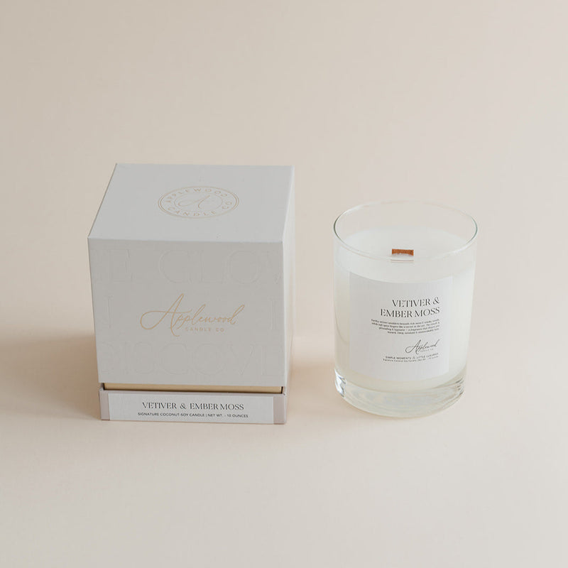 Vetiver & Ember Moss signature candle with box on beige background