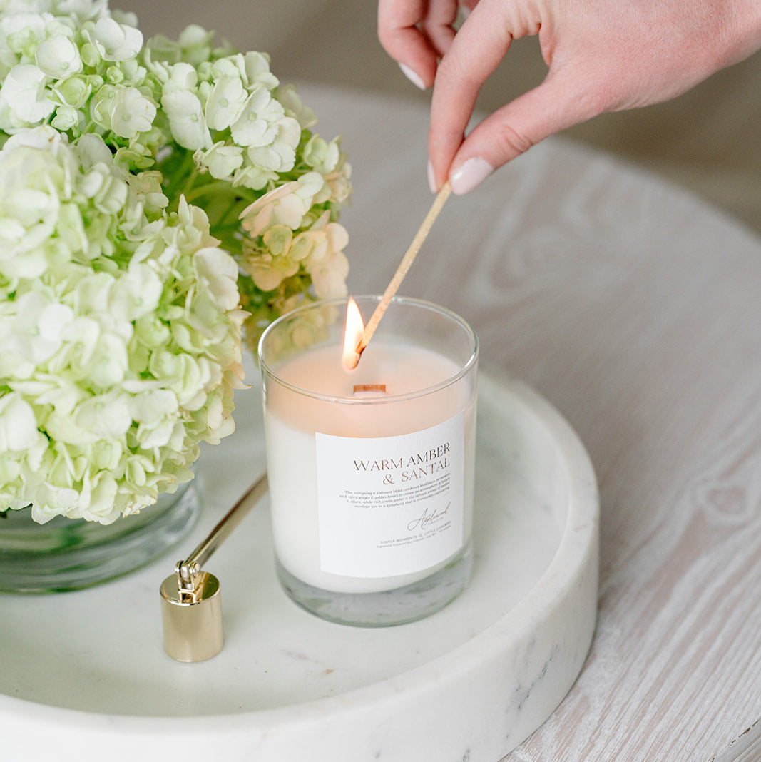 Warm Amber &amp; Santal Candle in glass jar being lit.