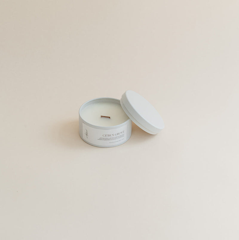 Travel Citrus & Grove candle in tin can on beige background.
