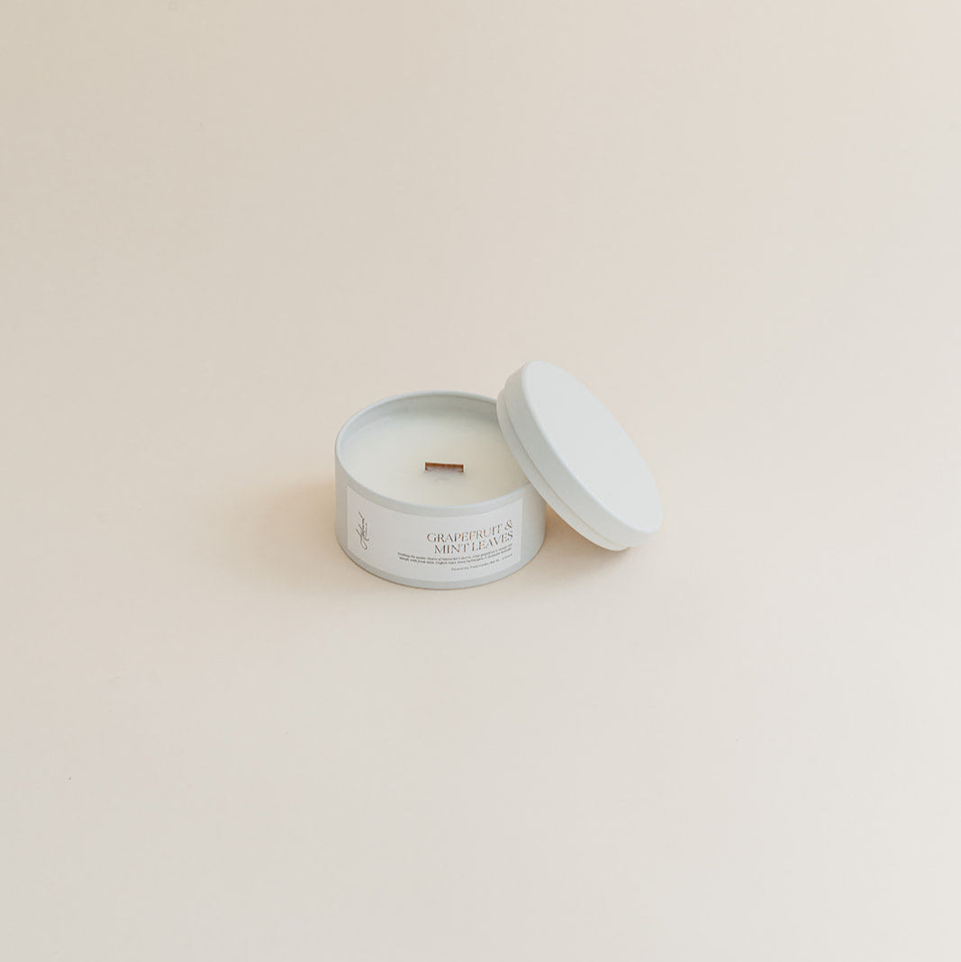 Travel Grapefruit & Mint Leaves candle in tin can on beige background.