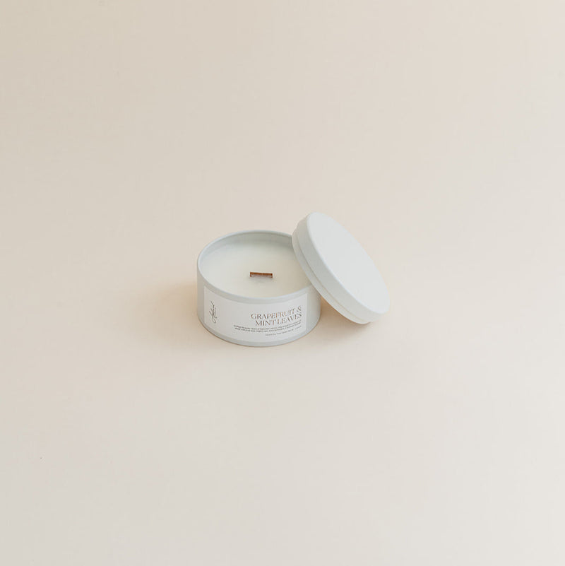 Travel Grapefruit & Mint Leaves candle in tin can on beige background.