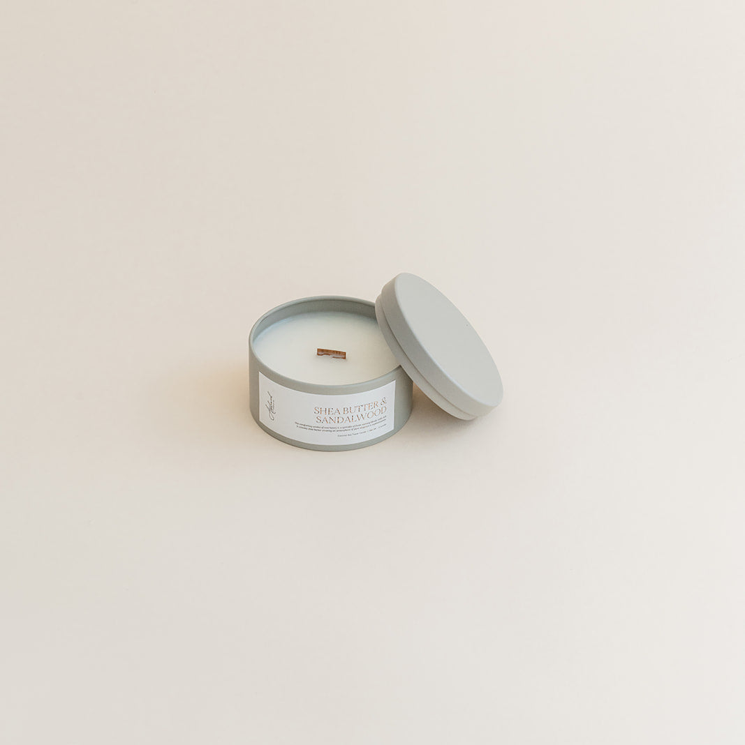 Travel Shea Butter &amp; Sandalwood candle in tin can on beige background.