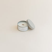 Travel Shea Butter & Sandalwood candle in tin can on beige background.
