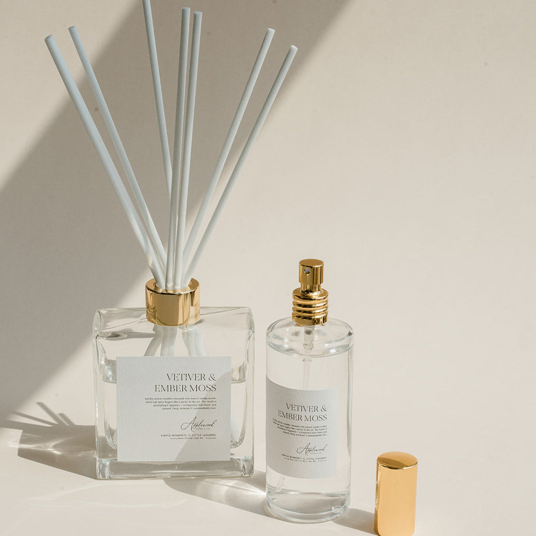 Luxury Flameless reed diffuser and linen spray in glass bottles with gold details, styled on beige background