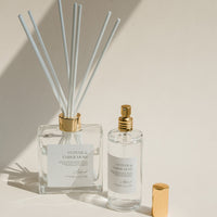 Luxury Flameless reed diffuser and linen spray in glass bottles with gold details, styled on beige background