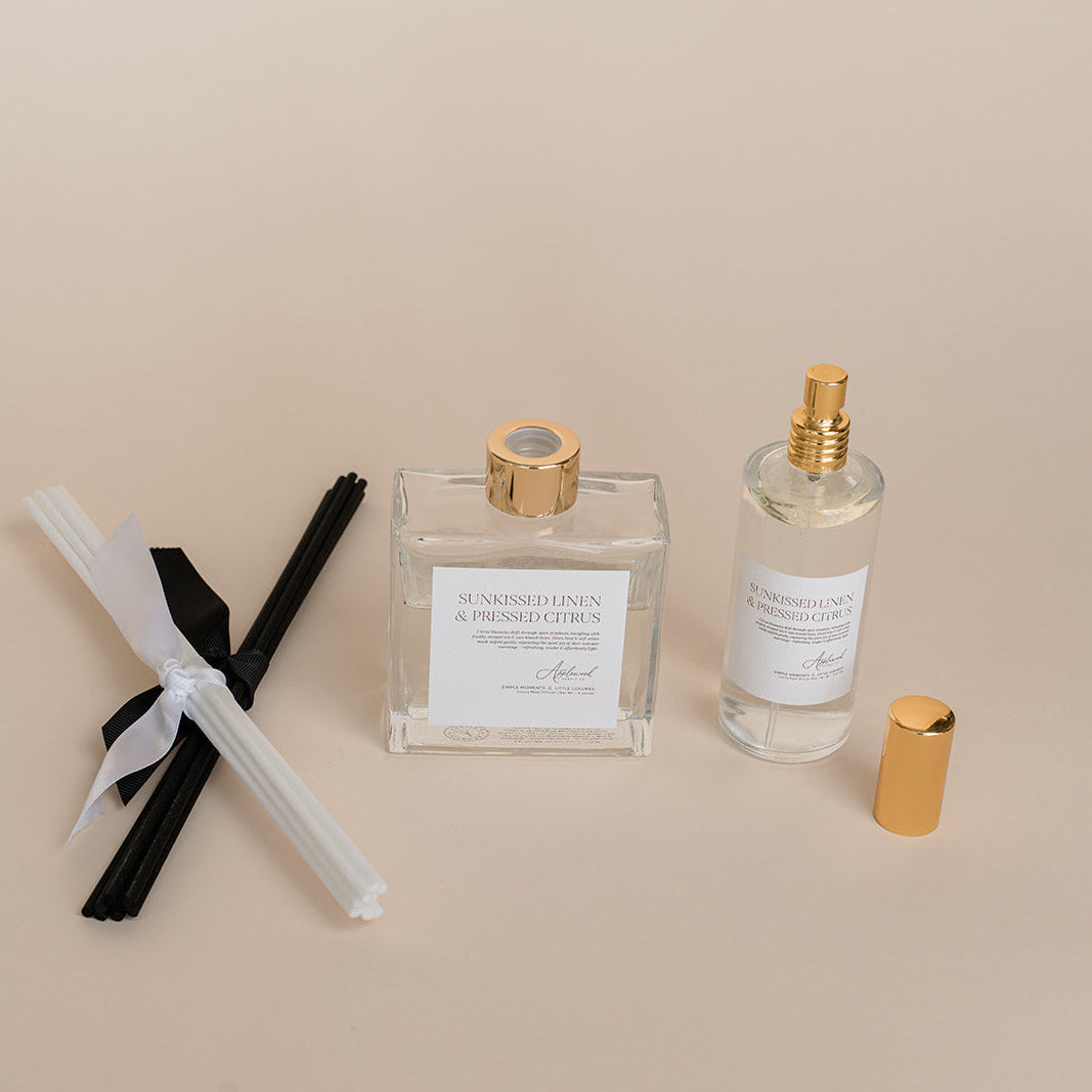 Two perfume bottles with gold caps and labels on a beige background