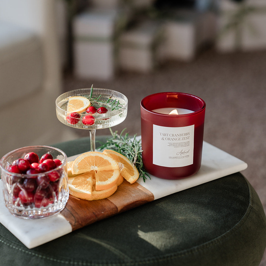 Candle and fruit platter on a table with a Christmas tree in the background