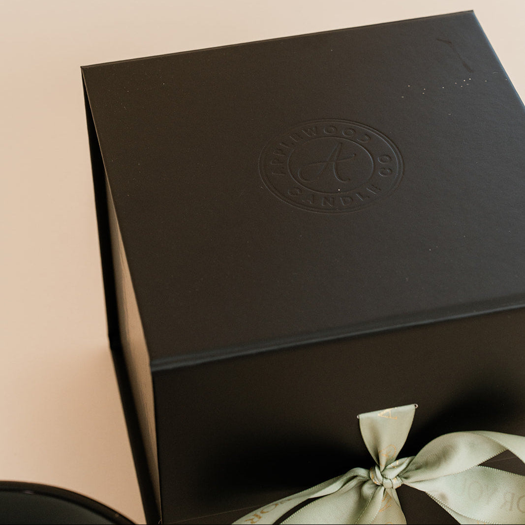 Black embossed box with a logo on a beige background