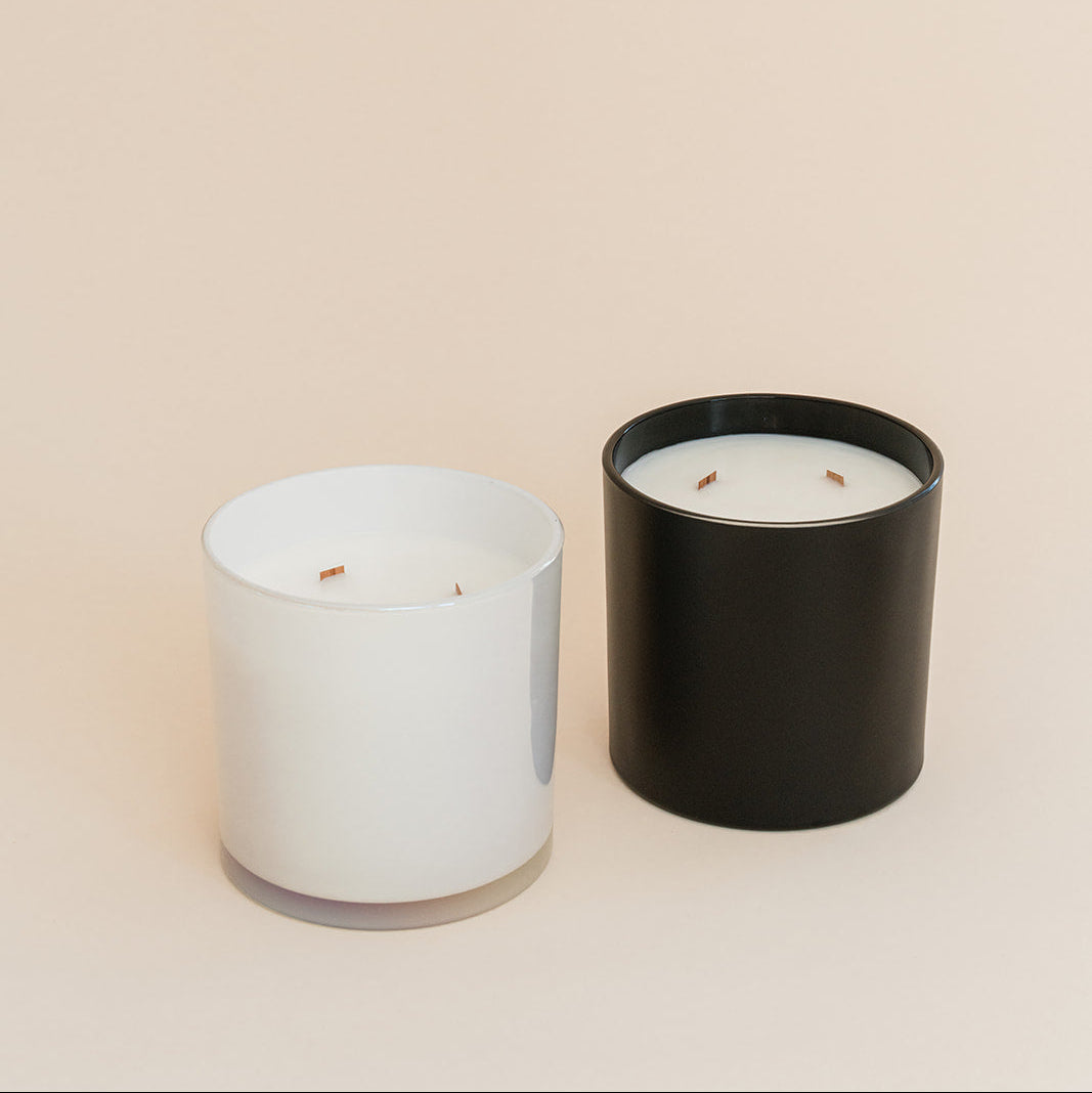 Two candles, one white and one black, on a beige background