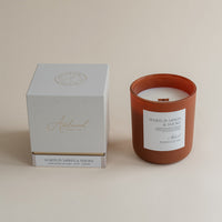 Candle with a white label and a matching box on a beige background
