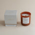 Candle with a white label and a matching box on a beige background