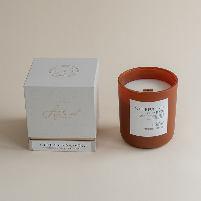 Candle with a white label and a matching box on a beige background
