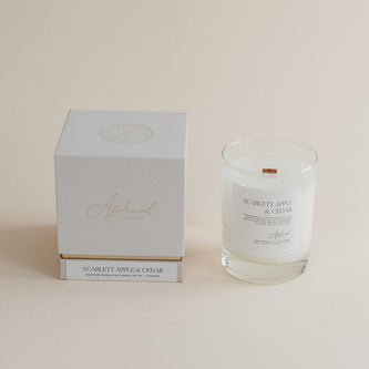 Glass candle with label and white box on a beige background