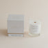 Glass candle with label and white box on a beige background