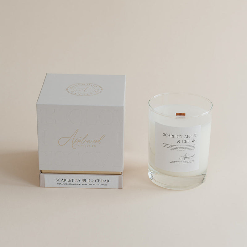 Glass candle with label and white box on a beige background