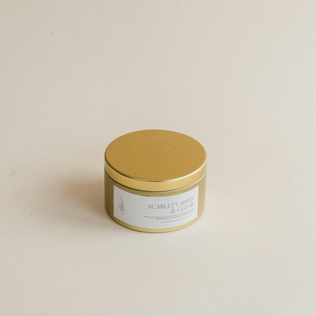 Gold candle jar with a label on a beige background