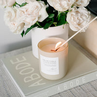 Shea Butter & Sandalwood Candle in glass frosted jar being lit.